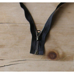 open-ended metal zip antique brass teeth color , single zip on a wooden table