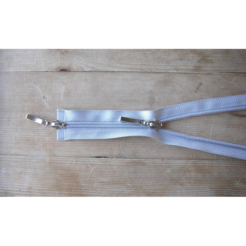 double slider zip - light grey - 50cm, placed on a wooden background, close up on the zip sliders