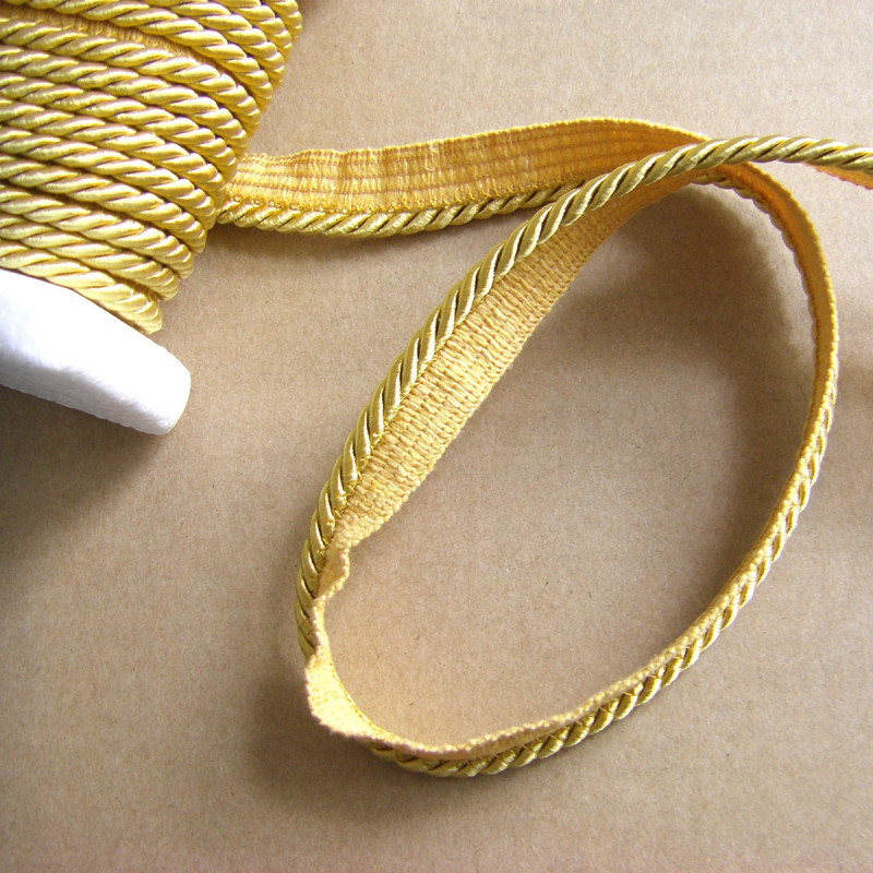 Flanged piping cord  in yellow gold color, 5mm wide piping , full reel on the table