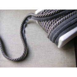 Twisted flanged piping cord 7mm wide in dark grey color from the reel on grey background