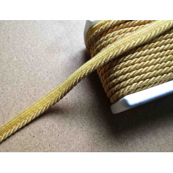 Twisted flanged piping cord 7mm wide in gold color on beige table