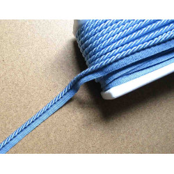 Twisted flanged piping cord 7mm wide in light blue color from the reel on grey background
