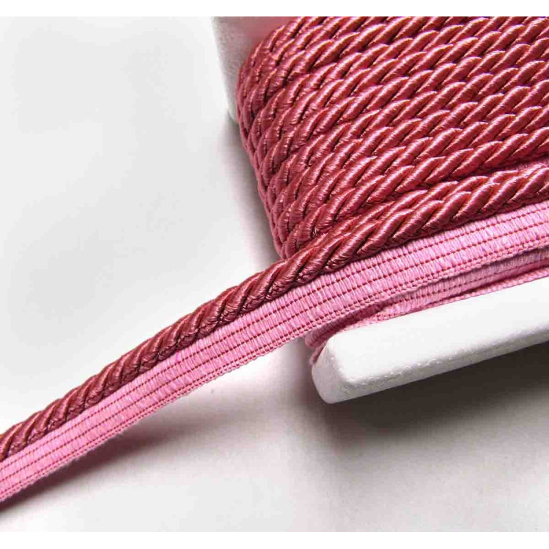 Twisted flanged piping cord 7mm wide in dusky pink color from the reel on white background
