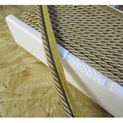 Twisted flanged piping cord 7mm wide in beige color from the reel on wooden table