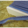 Twisted flanged piping cord 7mm wide in denim color from the reel on a wooden table