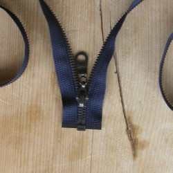 open-ended metal zip - navy -55cm - Antique brass color on a wooden table- close up