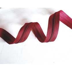 Plastic, nylon, Continuous zip - burgundy color, size 3, twisted on wooden table