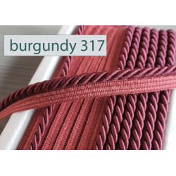 Twisted flanged piping cord 7mm wide in burgundy from the reel on a white table