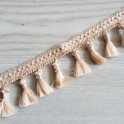 Tassels trim in beige sand color on the reel, 50mm long placed across the table