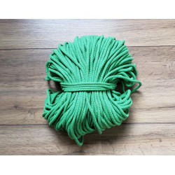 Cotton braided cord in fern green color, the full reel of cord on wooden table