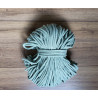 Cotton braided cord in sage green color, the full reel of cord on a wooden table