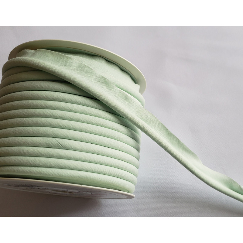 A full reel of plain, light green flanged piping cord on white background