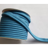 A full reel of plain, cornflower blue flanged piping cord on white background