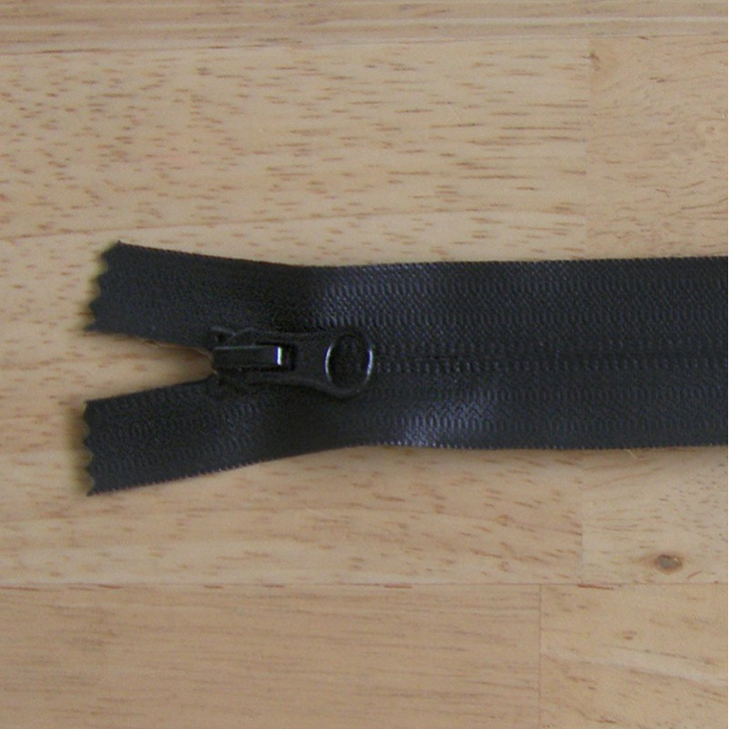 waterproof zip - black color - closed  end - 22cm long on a wooden background