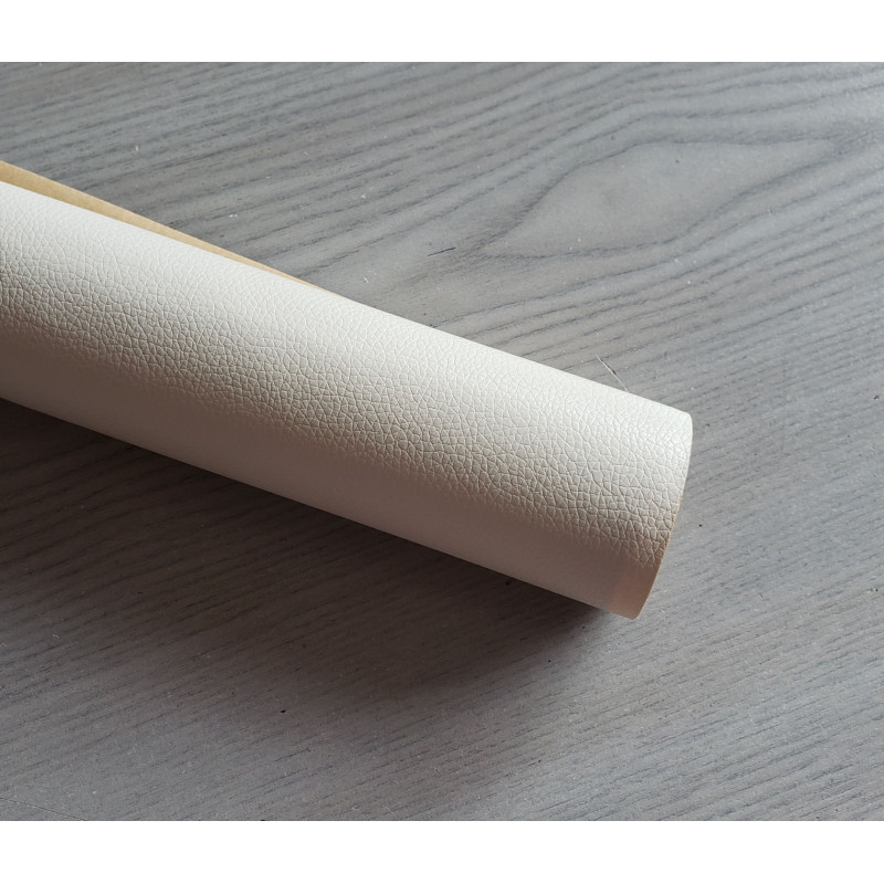 Self-Adhesive Faux leather fabric - cream, the roll of the fabric placed across the grey table