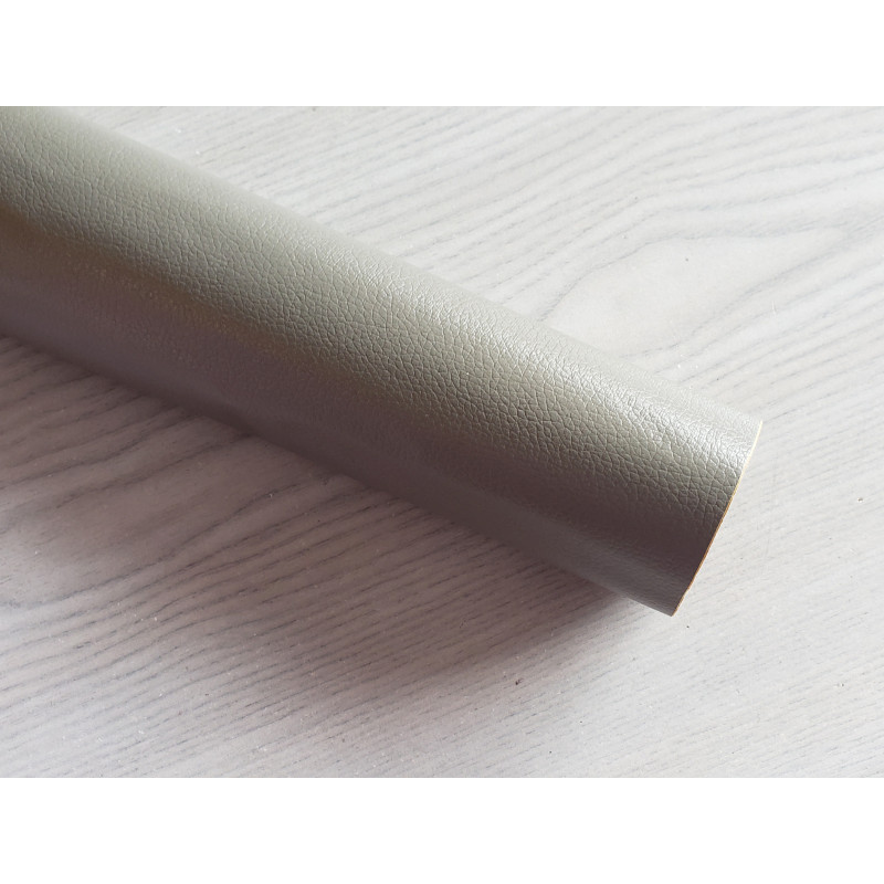 Self-Adhesive Faux leather fabric - darker grey, the roll of the fabric placed across the grey table