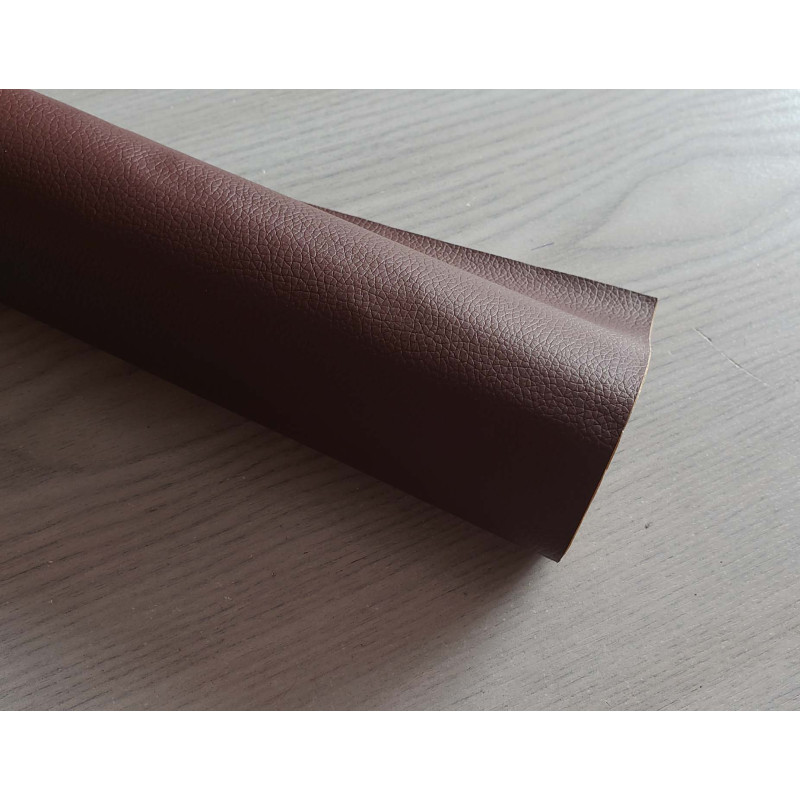 Self-Adhesive Faux leather fabric - darker brown, the roll of the fabric placed across the grey table