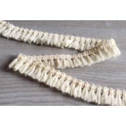 Short flexible wool fringe 25mm - cream color, placed on a grey table