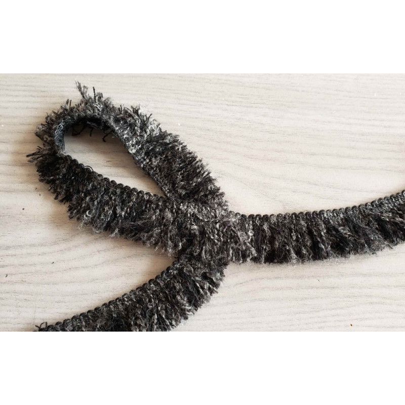 Short flexible wool fringe 30mm - dark grey blend color, placed on a grey table