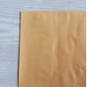 Self-Adhesive Faux leather fabric - caramel, the sheet of the fabric placed on a grey table, close up