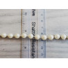 round pearl trim - ivory  twisted on a grey background with a ruler