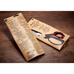 Dressmaking scissors in a package - 9in or 23cm, placed on a wooden table with a piece of the fabric