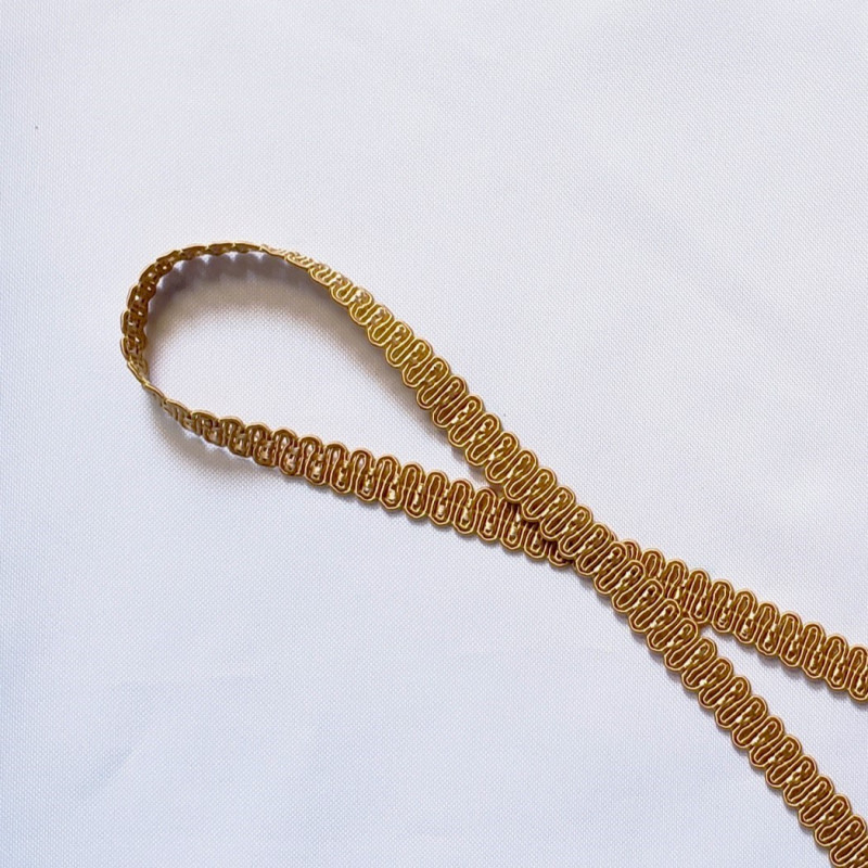 Upholstery braid 14mm - Gold Beige color, a loop shape placed on a white background