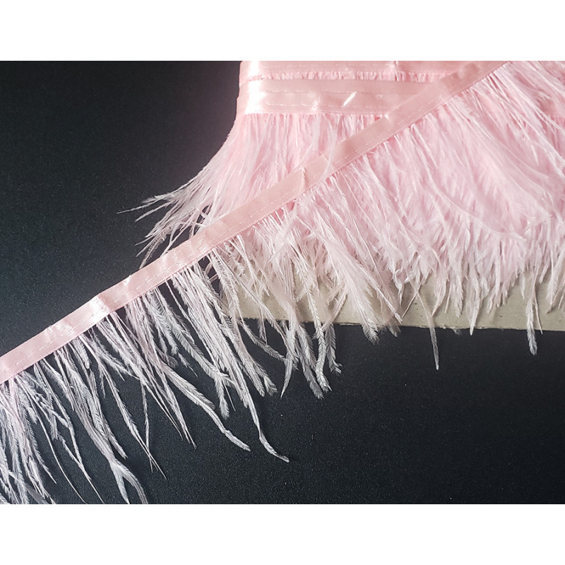 Ostrich feather fringe trim - light pink color, placed on a black, contrasting background