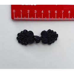 Frog fastener- black with beads, placed on a white background with a red ruler to show the size