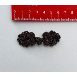 Frog fastener- dark brown with beads, placed on a white background with a red ruler to show the size