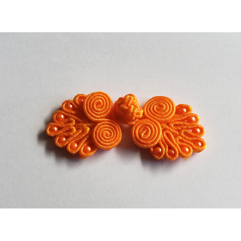 Frog fastener- orange with beads, placed on a white background